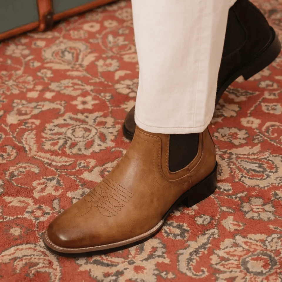 Brown leather Chelsea boots on a patterned carpet